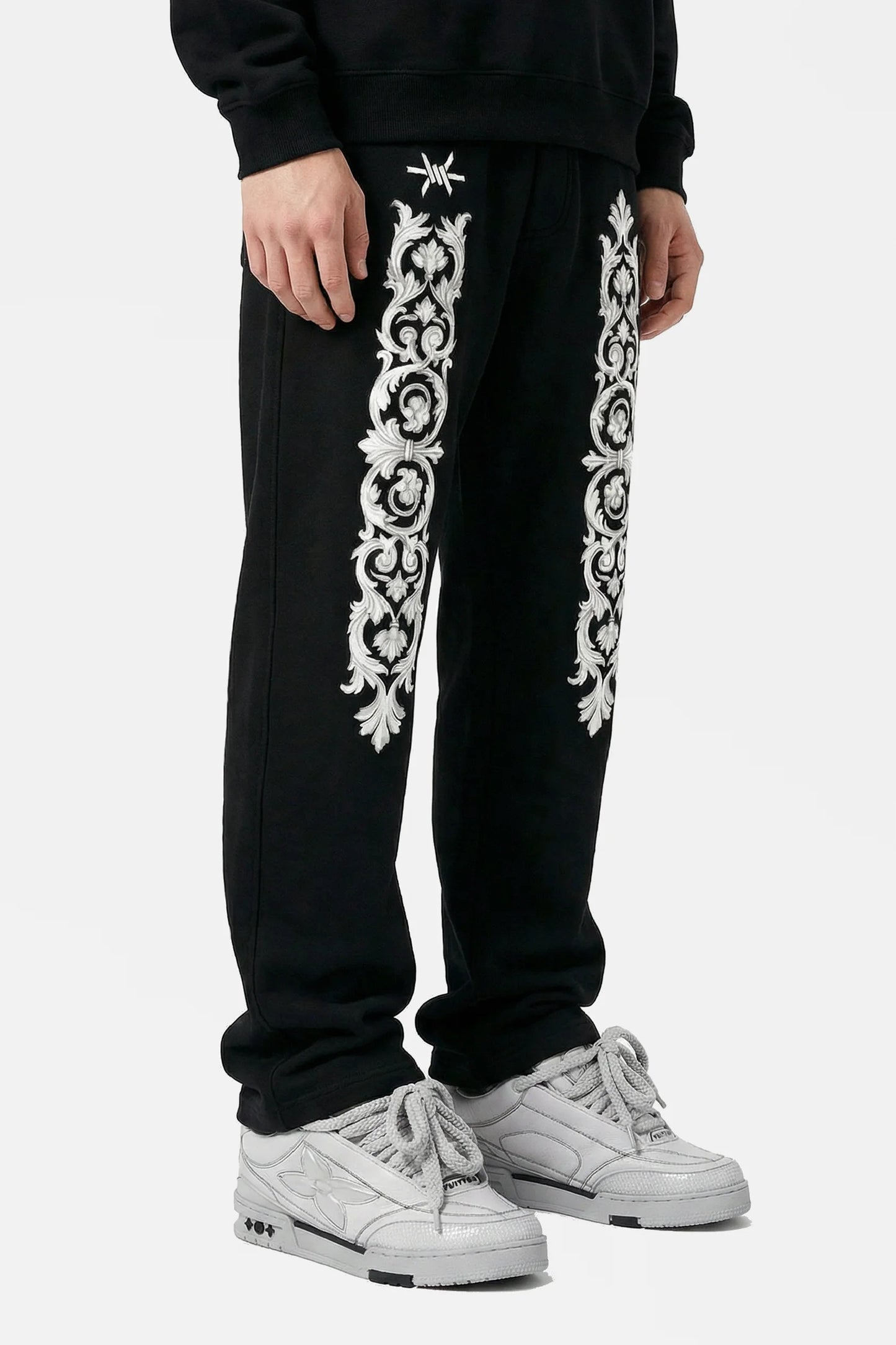 Black sweatpants with white floral patterns on a white background