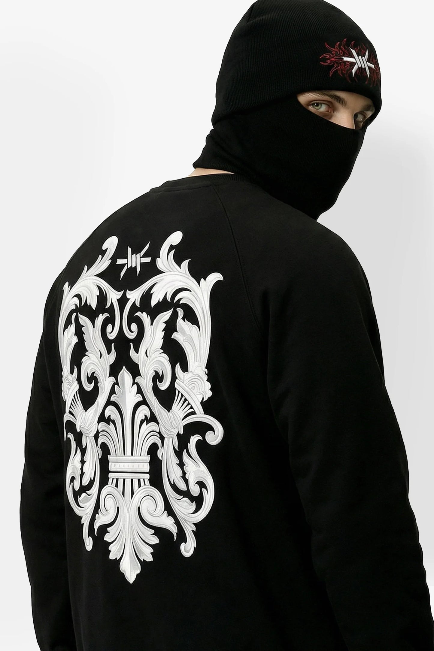 Person wearing a black hoodie with a white intricate design on the back, against a plain background.