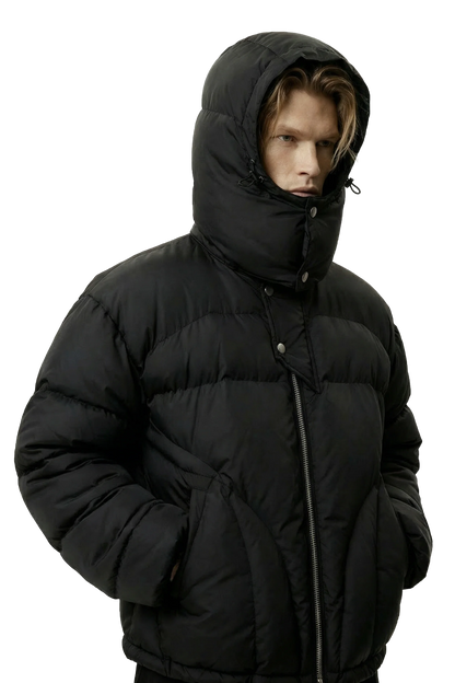 Person wearing a black puffer jacket with a hood on a white background