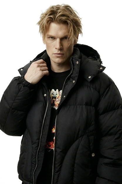 Man wearing a black puffer jacket over a graphic t-shirt on a transparent background