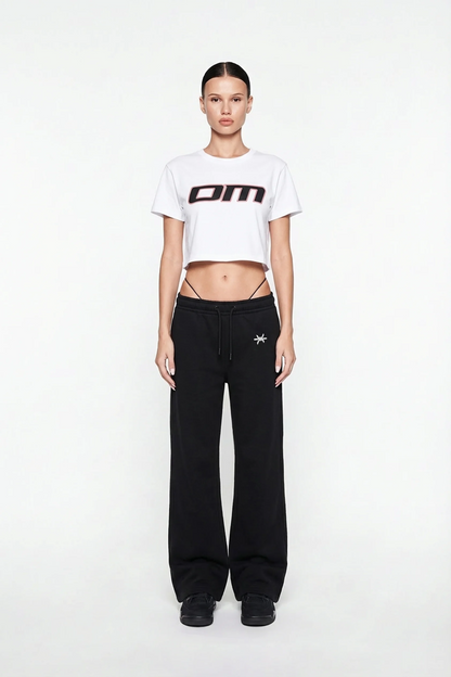 Ominous OM Cropped White Tee - Person wearing a white cropped t-shirt with a logo and black pants on a white background