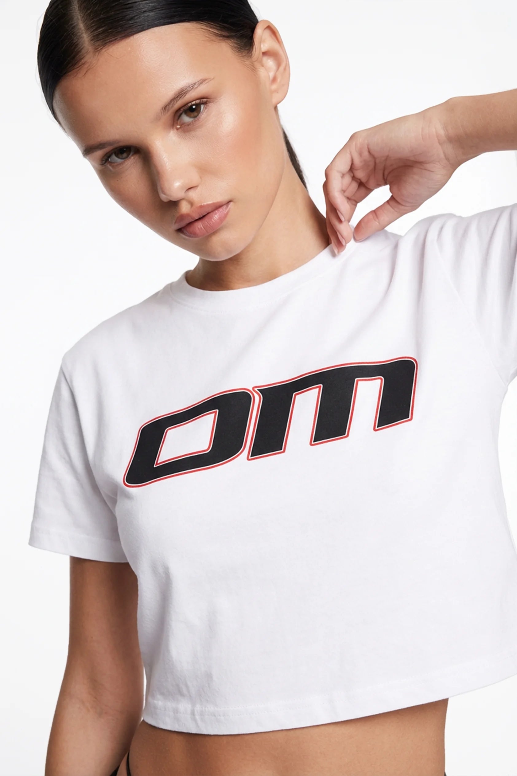 Ominous OM Cropped White Tee - Model woman wearing a white luxury brand cropped t-shirt with a logo on a plain background
