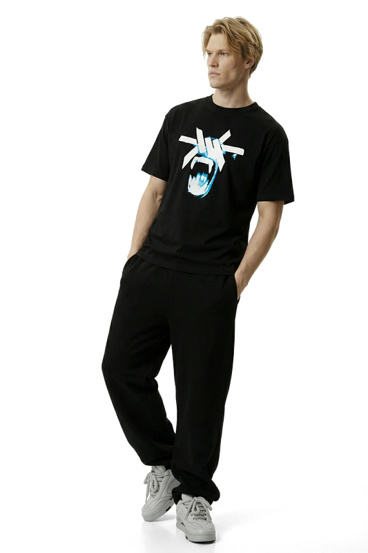 Person wearing a black t-shirt with a white and blue monkey's face graphic design and black pants on a white background