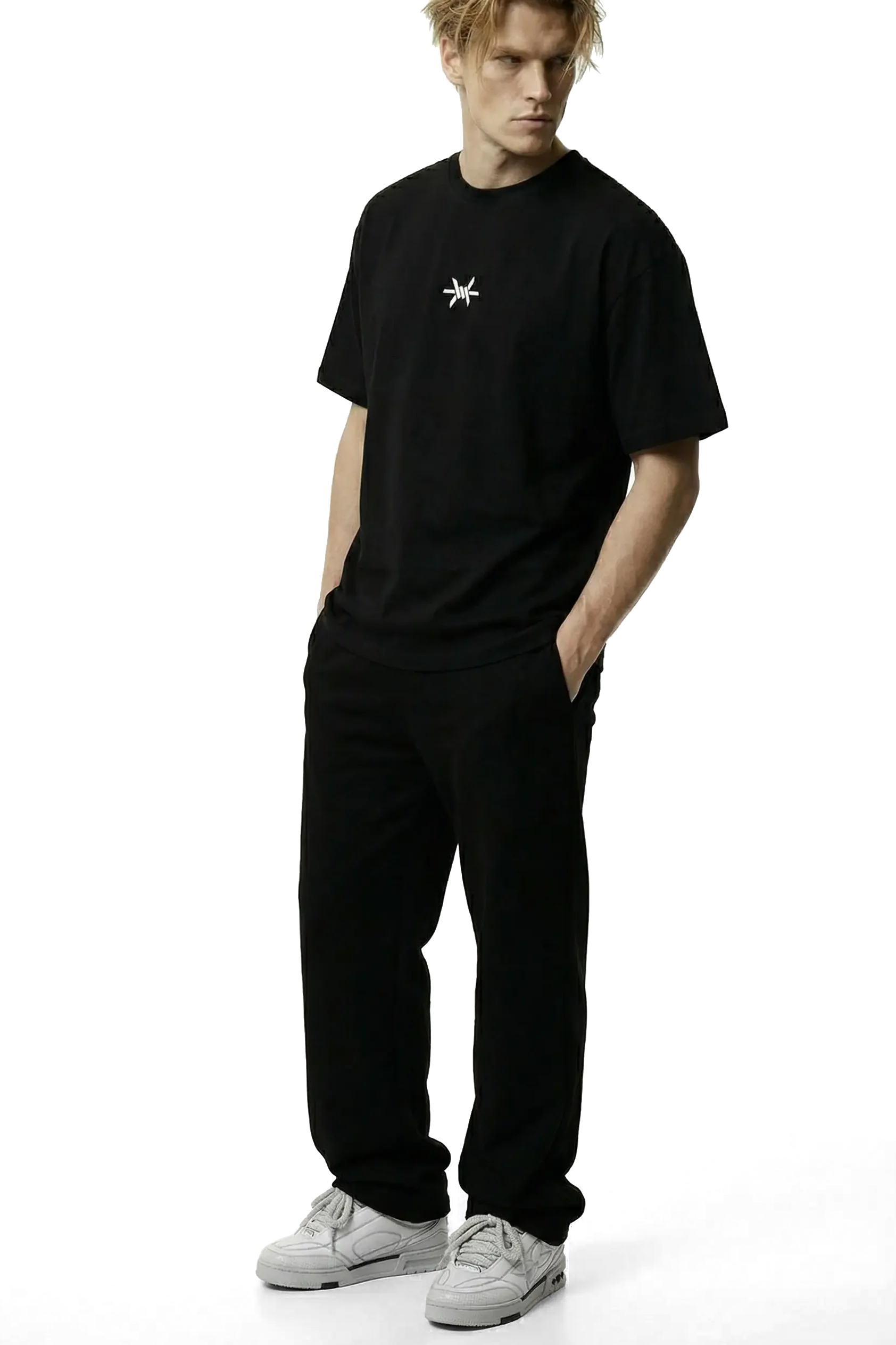 Ominous Ascendance Heavyweight Tee - Man wearing an oversized heavyweight black t-shirt with a small white 'Ominous' logo in the upper centre chest area and black pants on a white background
