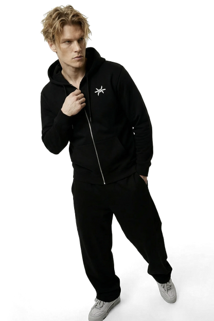 Person wearing a black tracksuit with a logo on a white background