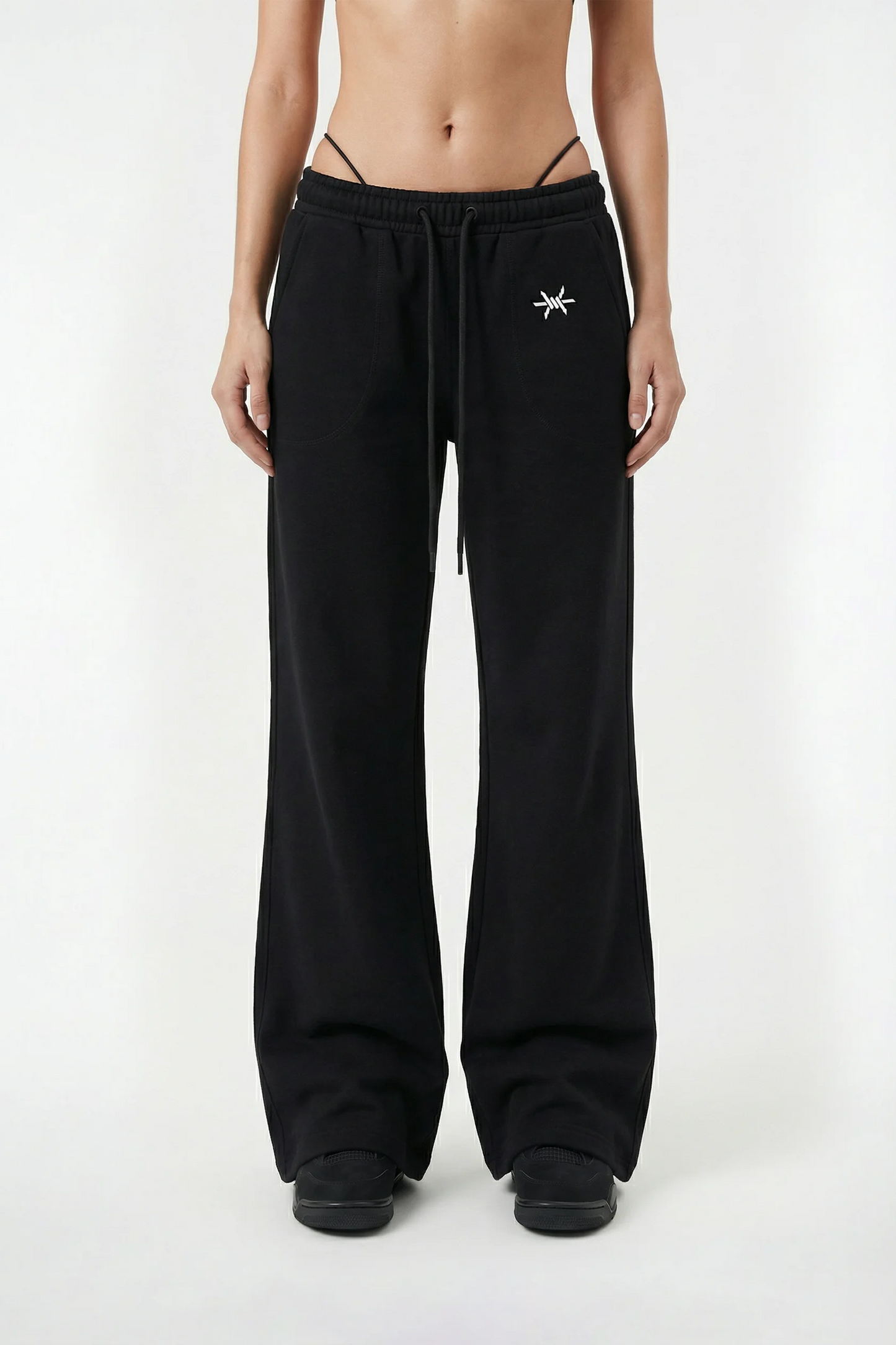 Person wearing black sweatpants with a small white logo on a white background