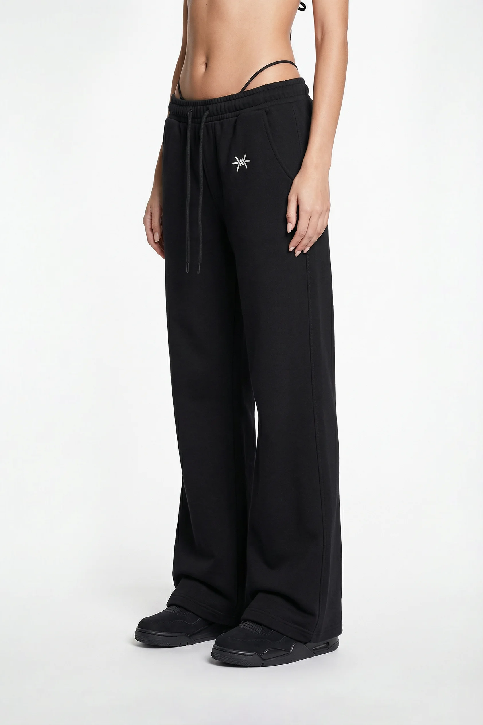 Person wearing black wide-leg pants with a star detail on a white background