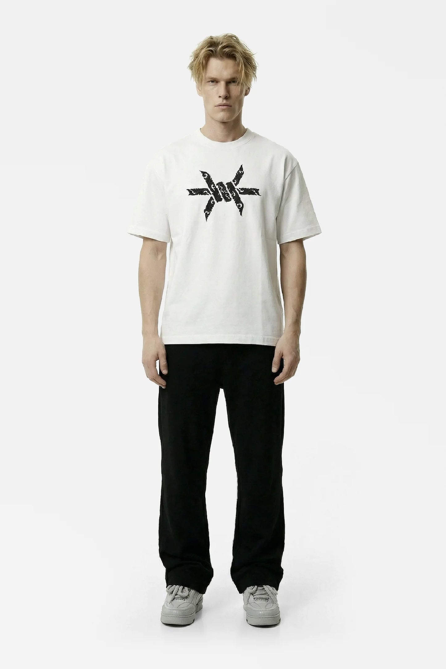 Man wearing a white t-shirt with a black baroque 'Ominous' brand logo graphic design on a white background