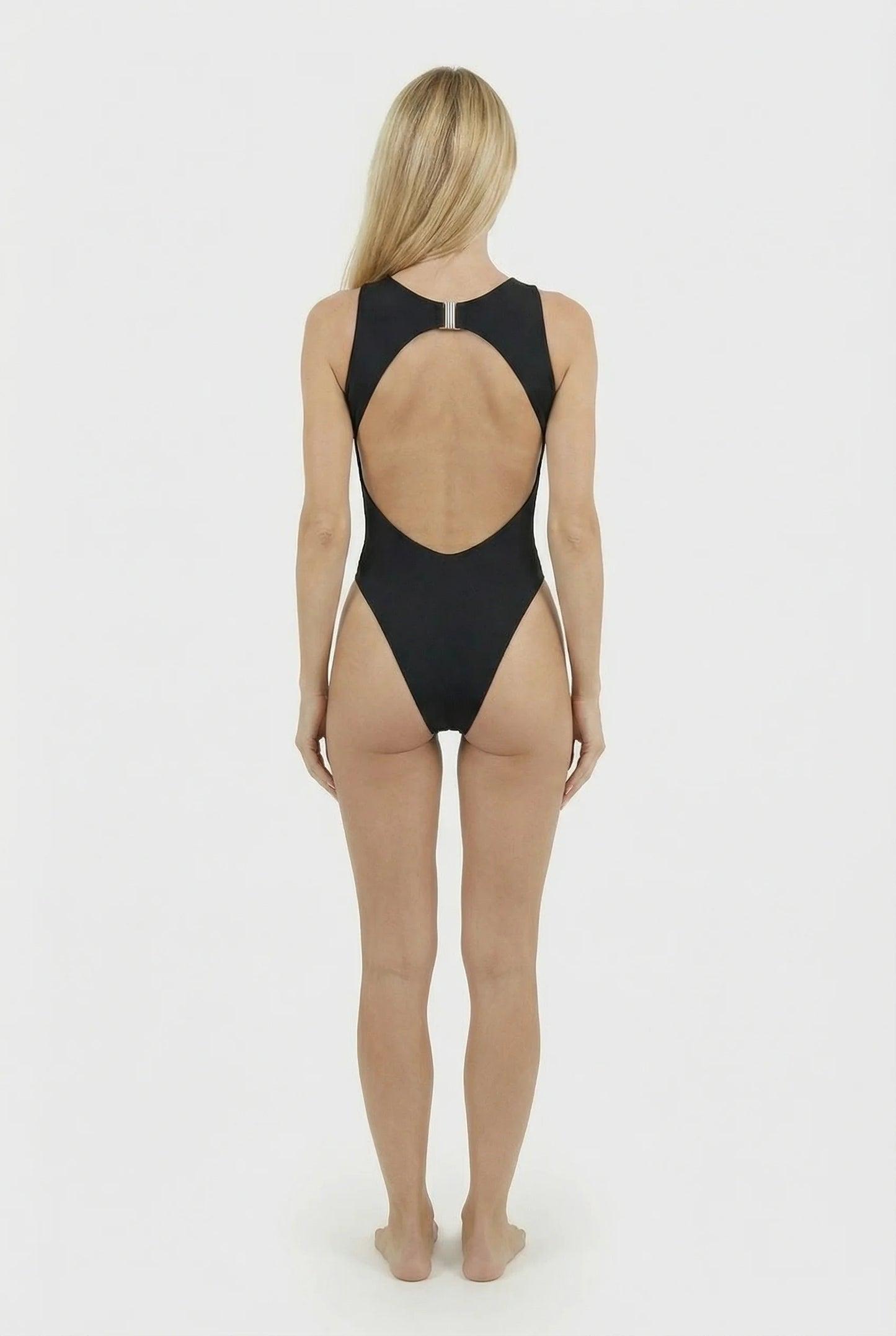 Woman wearing a black swimsuit with a sheer back on a white background