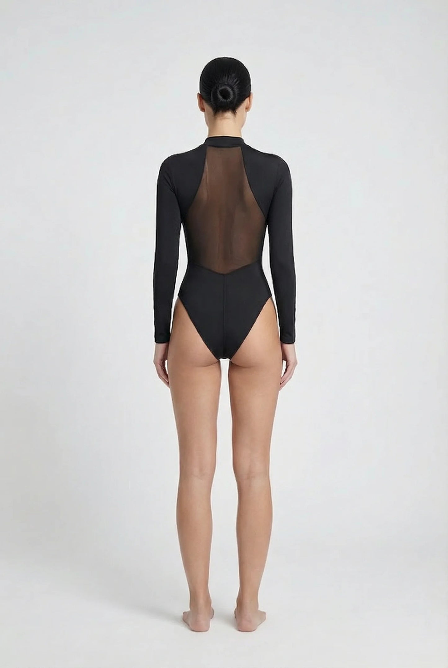 Person wearing a black 'Ominous' brand swimsuit with sheer mesh back on a white background