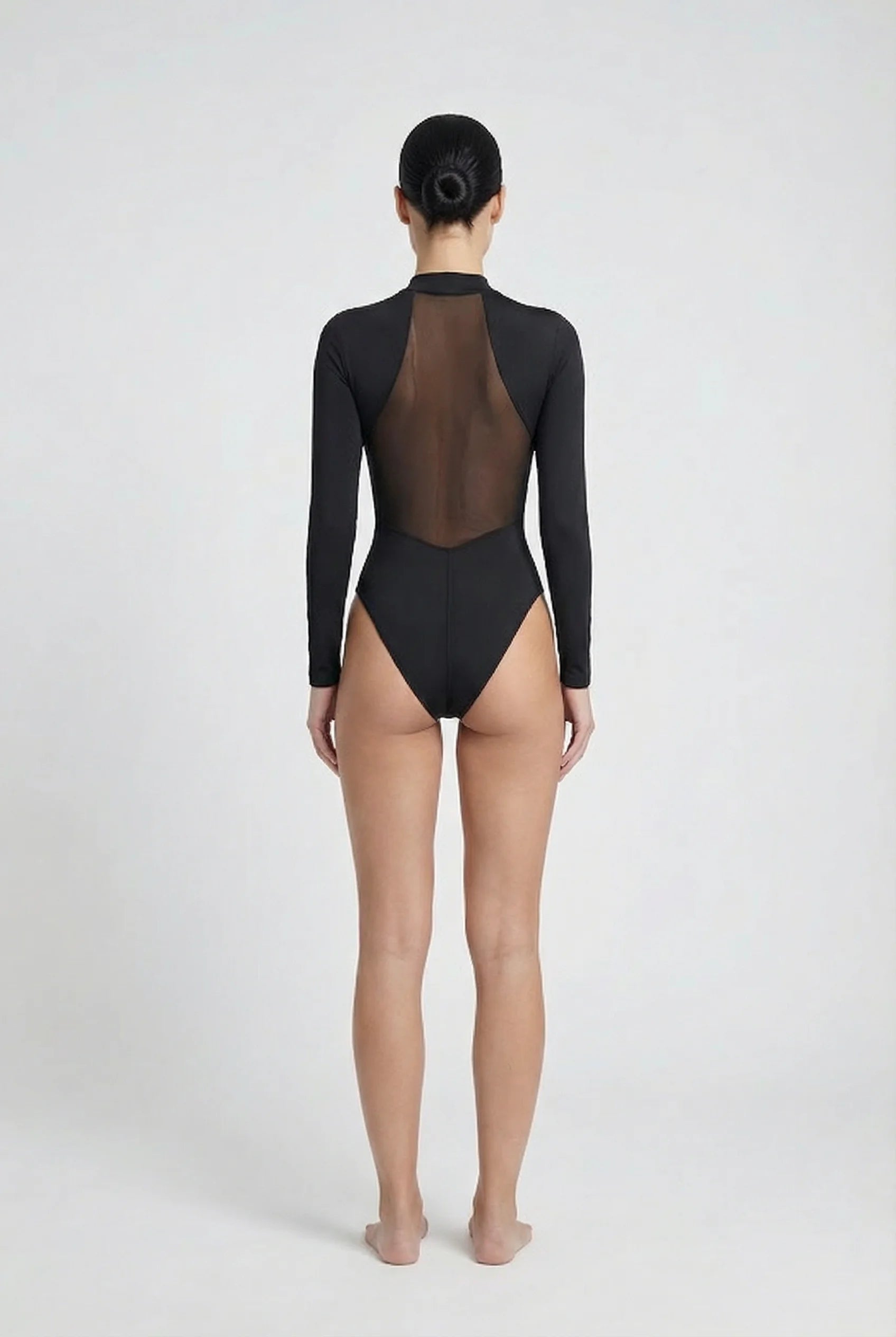 Person wearing a black 'Ominous' brand swimsuit with sheer mesh back on a white background