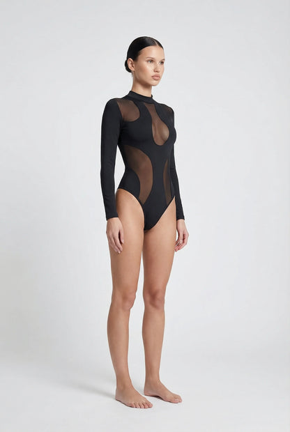 Model wearing an 'ominous' brand black bodysuit with sheer panels on a white background