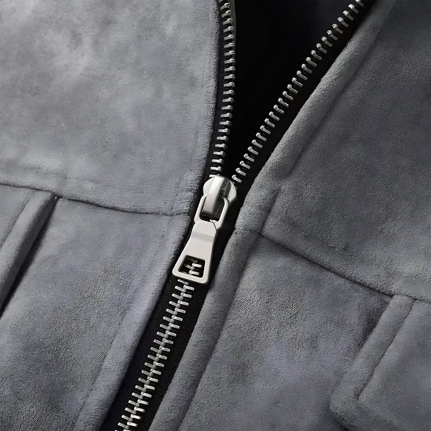 Very close up photo of a luxury metal zipper on a gray suede lounge overshirt jacket